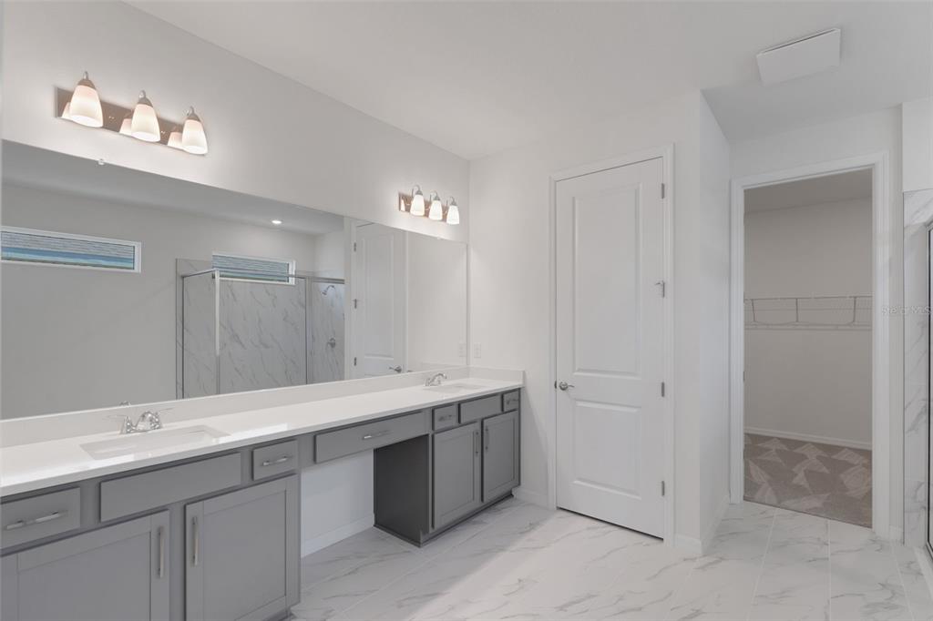 A bathroom features a double vanity with gray cabinets, white countertops, and a large mirror — 17013 GREAT HERON LANE, PUNTA GORDA, FL