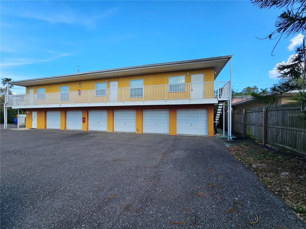 A two-story yellow building features a row of ground-level garages and an upper-level balcony — 119 N EVERGREEN AVENUE UNIT 203, CLEARWATER, FL