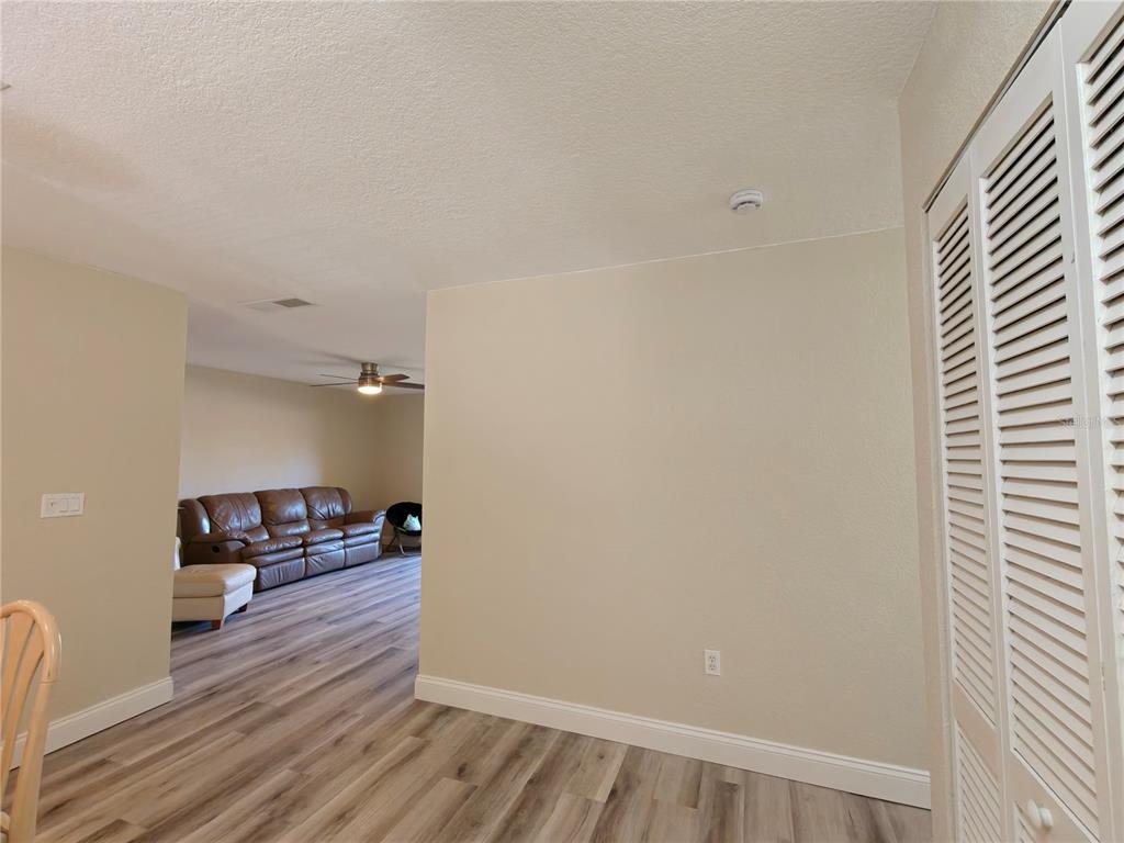 A view from a dining area looking into a living room with wood-look flooring — 1810 NW 23RD BOULEVARD UNIT 165, GAINESVILLE, FL
