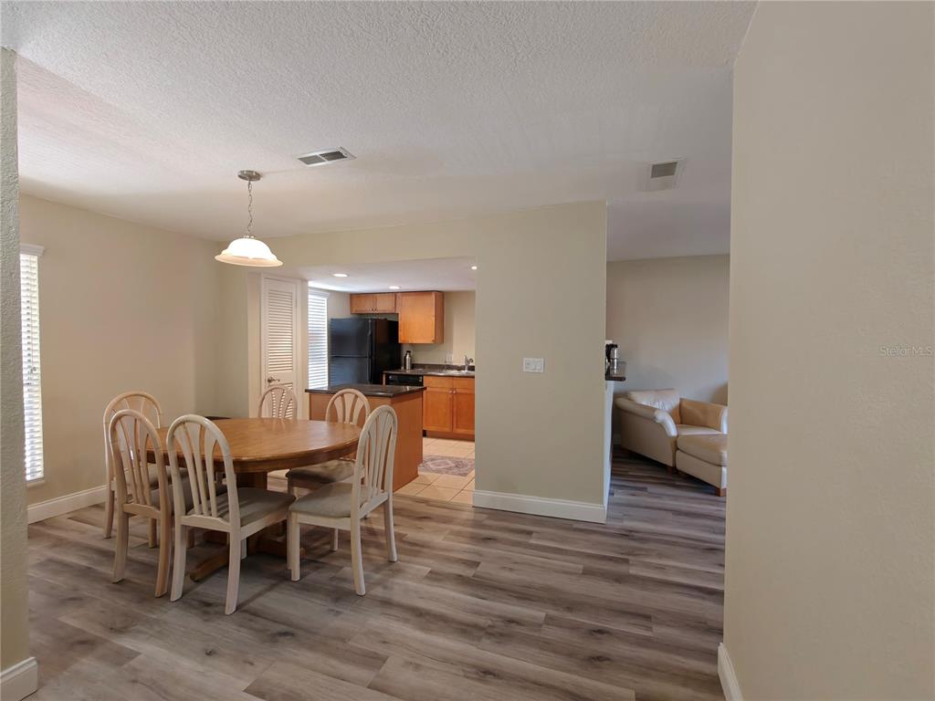 A dining area with a wooden table and chairs opens into a kitchen with cabinets — 1810 NW 23RD BOULEVARD UNIT 165, GAINESVILLE, FL