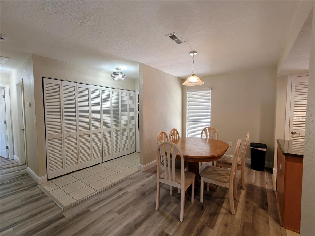 A dining area features a wooden table, four chairs, tile and wood-look flooring, and closets — 1810 NW 23RD BOULEVARD UNIT 165, GAINESVILLE, FL