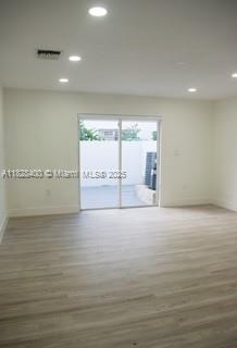 An empty room with light wood-look flooring, recessed lighting, and a sliding glass door — 968 N 18th Ct, Hollywood FL 33020, HOLLYWOOD, FL