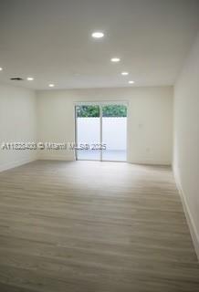 An empty room with light wood-look flooring, recessed lighting, and a sliding glass door — 968 N 18th Ct, Hollywood FL 33020, HOLLYWOOD, FL