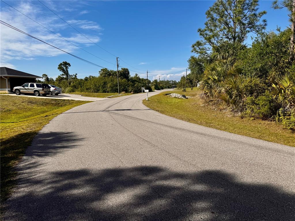 A paved road curves through a residential area with a house and parked vehicles — SAWYER CIRCLE, NORTH PORT, FL