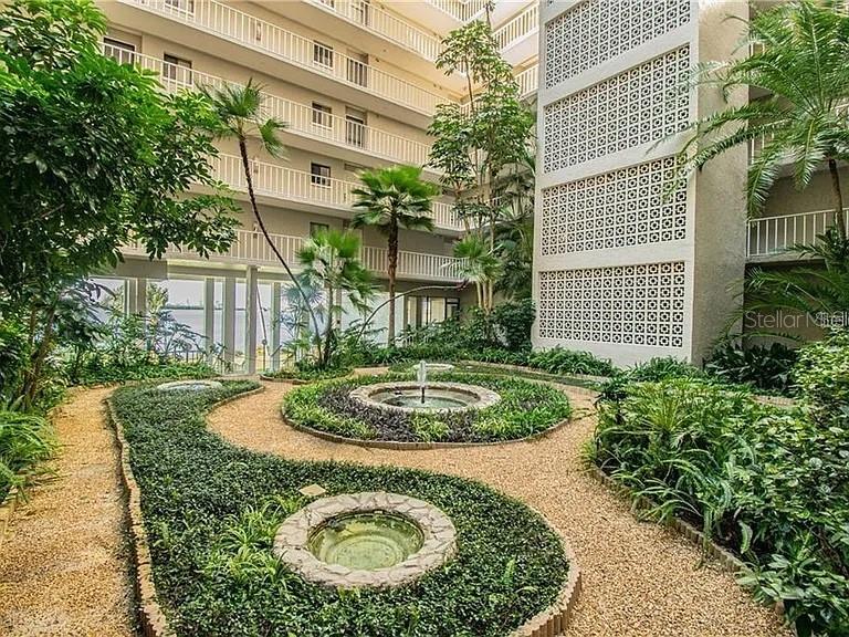 An outdoor courtyard features a gravel path, circular garden beds, and a small stone fountain — 500 N OSCEOLA AVENUE UNIT 403, CLEARWATER, FL