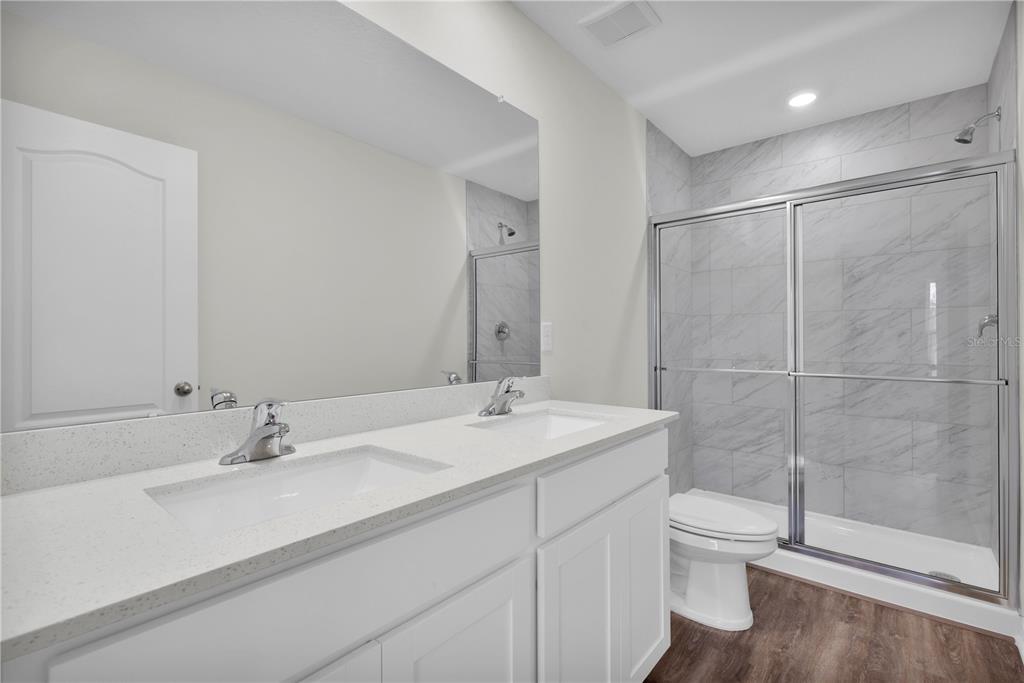 A bathroom features a double vanity with white cabinets, quartz countertops, and a glass-enclosed shower — 15777 SW 23RD COURT ROAD, OCALA, FL