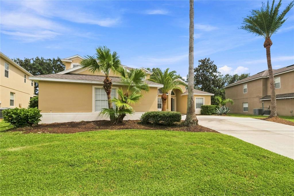 A tan single-story house with a palm tree in the front yard and a driveway — 3469 FOREST RIDGE LANE, KISSIMMEE, FL