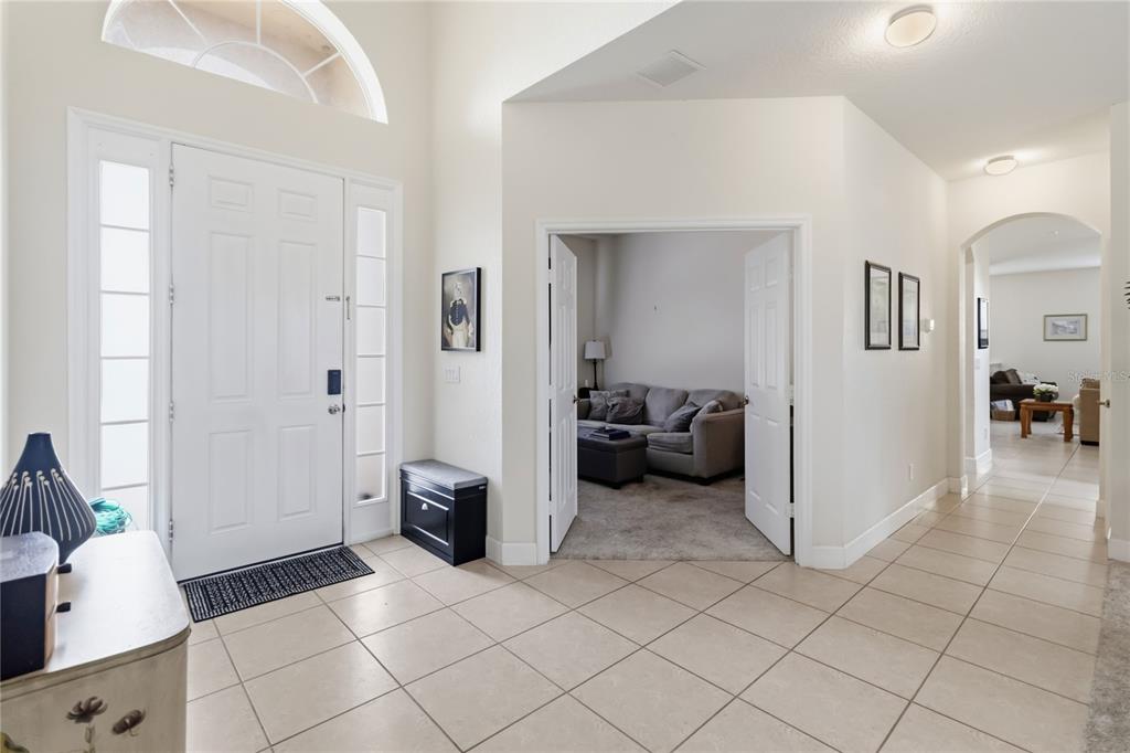 A bright entryway features tile flooring, a white front door, and double doors to a den — 3469 FOREST RIDGE LANE, KISSIMMEE, FL