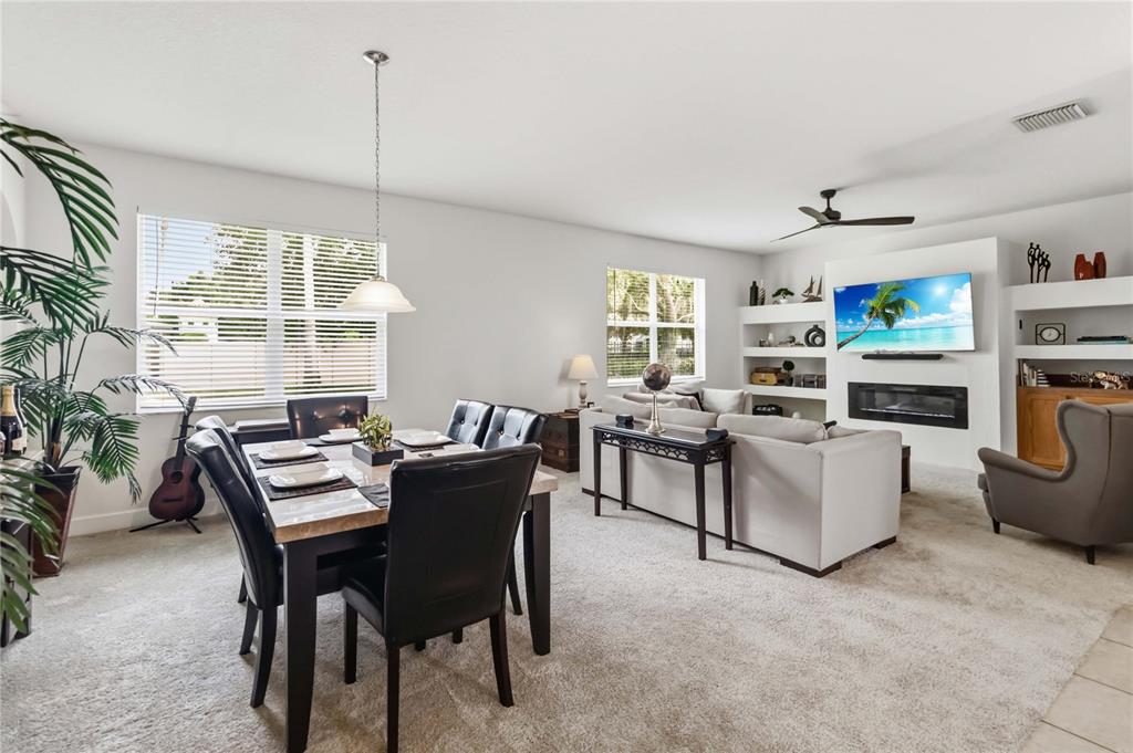 A dining area and living room with carpeted floors, a fireplace, and built-in shelving — 3469 FOREST RIDGE LANE, KISSIMMEE, FL