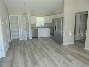 A kitchen with white cabinets, stainless steel appliances, and light wood-look flooring — 1 FISHER TERRACE TRACE UNIT 201, OCKLAWAHA, FL