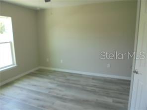 An empty bedroom features light-colored wood-look flooring, neutral walls, and a single window — 1 FISHER TERRACE TRACE UNIT 201, OCKLAWAHA, FL