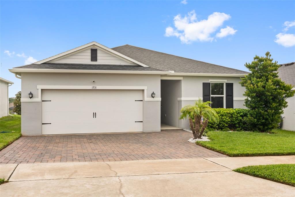 A single-story house features a two-car garage, a paved driveway, and a small front lawn — 1731 WILSON PRAIRIE CIRCLE, GROVELAND, FL