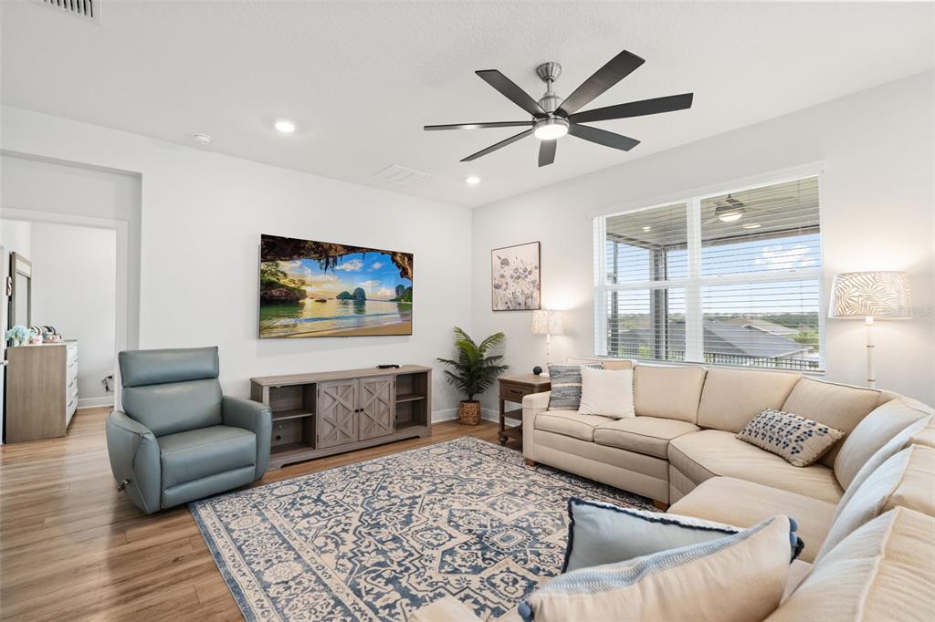 A living room features a sectional sofa, a blue armchair, a television, and a rug — 1731 WILSON PRAIRIE CIRCLE, GROVELAND, FL