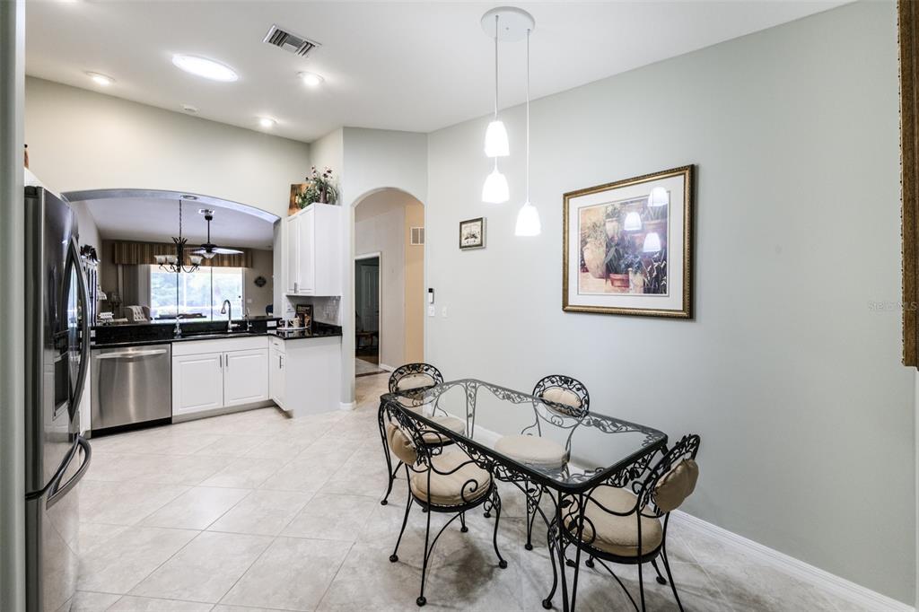 A dining area with a glass-topped table and metal chairs sits beside a white kitchen — 327 MONACO DRIVE UNIT 12, PUNTA GORDA, FL