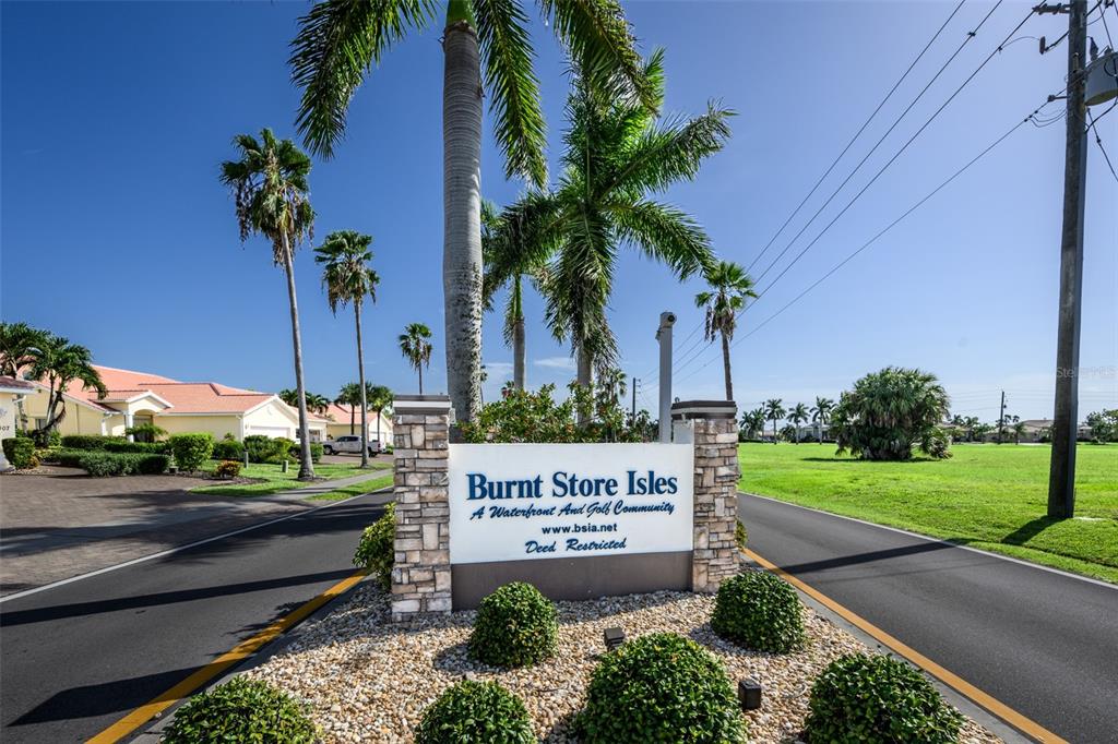 A stone monument sign for Burnt Store Isles stands at the entrance of a community — 327 MONACO DRIVE UNIT 12, PUNTA GORDA, FL