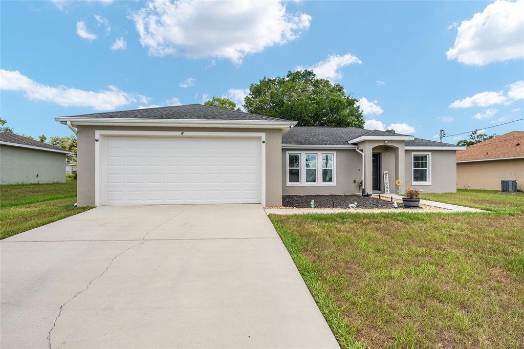 A single-story house with a two-car garage, gray exterior, and a concrete driveway — 6 JUNIPER PASS DRIVE, OCALA, FL