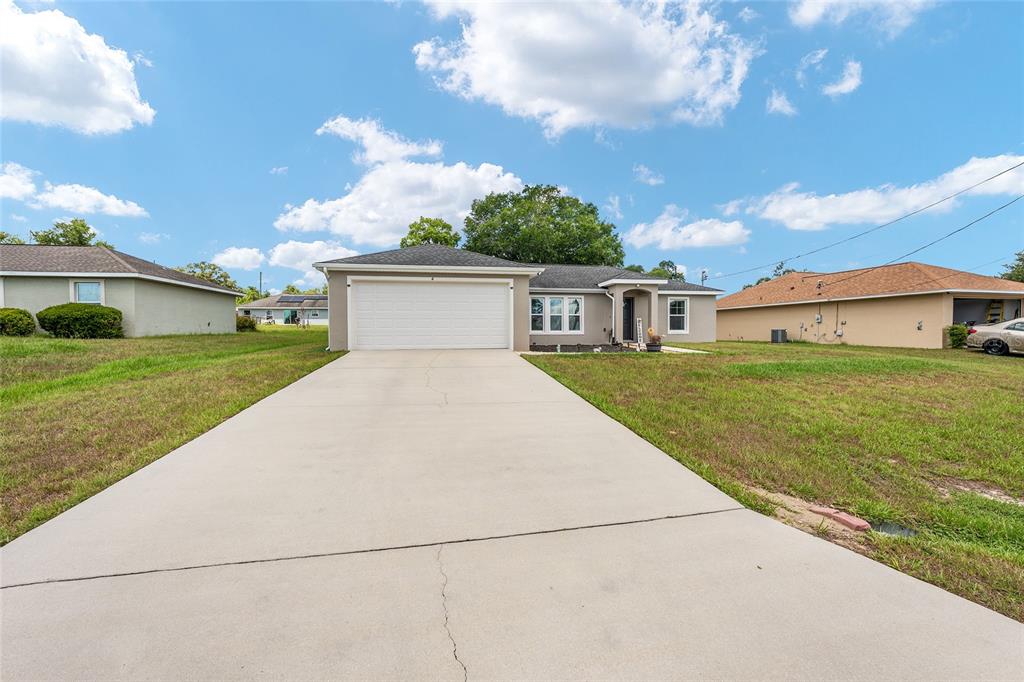 A single-story house with a two-car garage and a concrete driveway under a blue sky — 6 JUNIPER PASS DRIVE, OCALA, FL