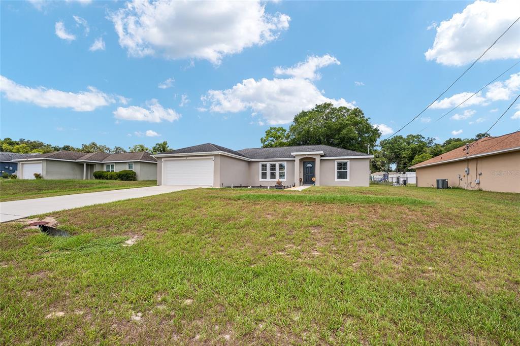 A single-story suburban house with a two-car garage and a large front lawn — 6 JUNIPER PASS DRIVE, OCALA, FL