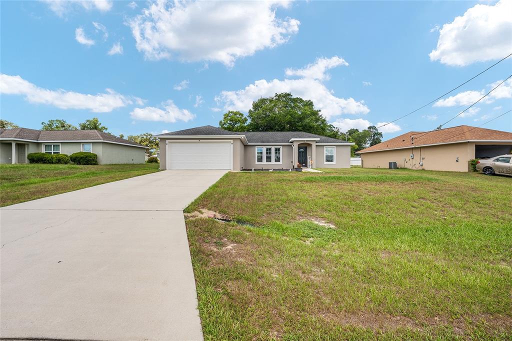 A single-story house with a two-car garage, gray siding, and a concrete driveway — 6 JUNIPER PASS DRIVE, OCALA, FL
