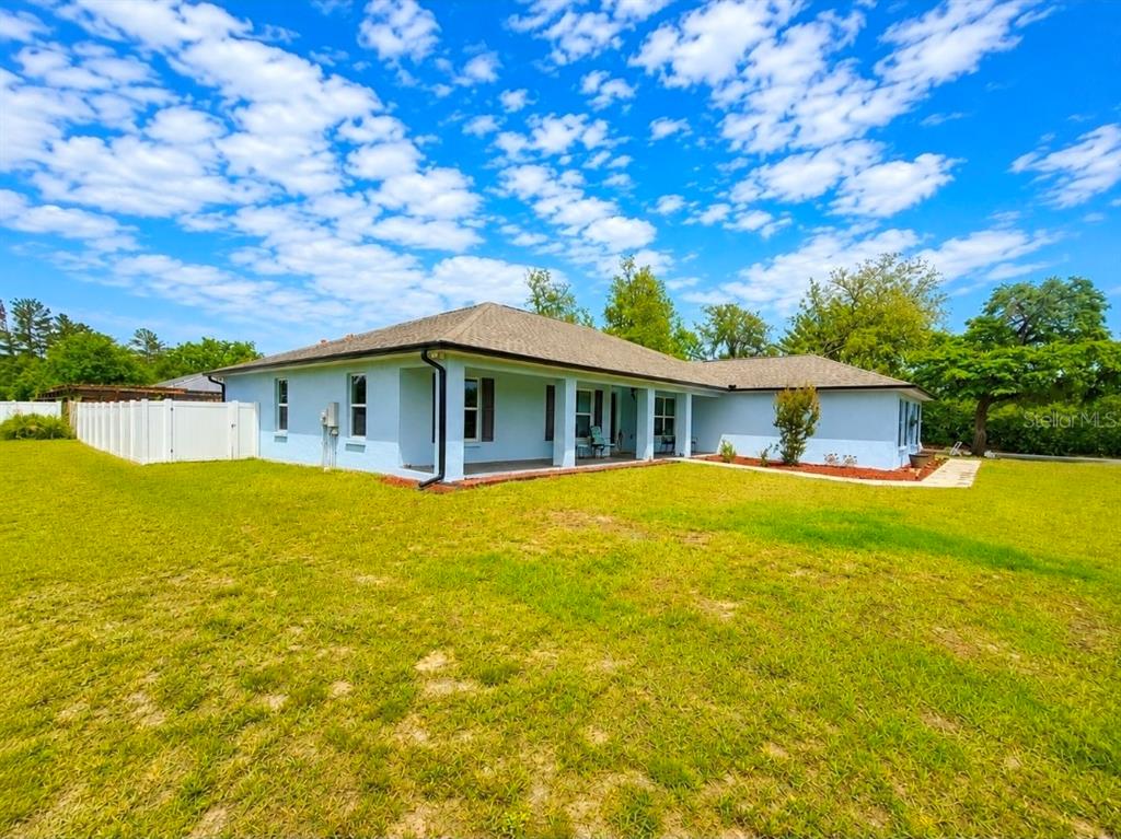 The exterior of a light blue, single-story house with a covered patio and white fence — 3805 SW 115TH STREET, OCALA, FL