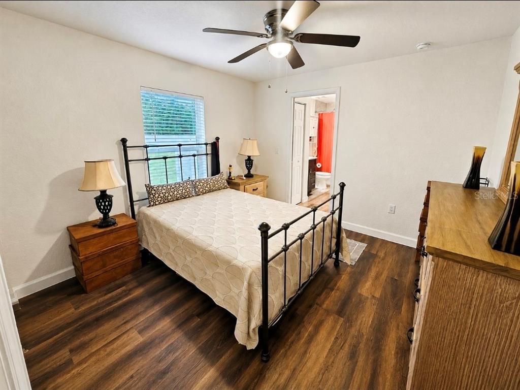 A bedroom features a metal bed frame, wood-look flooring, a ceiling fan, and an attached bathroom — 3805 SW 115TH STREET, OCALA, FL