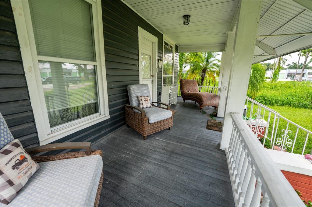 A covered front porch features dark wood siding, wicker chairs, and a chaise lounge — 2024 OLD LAKE MARY ROAD, SANFORD, FL