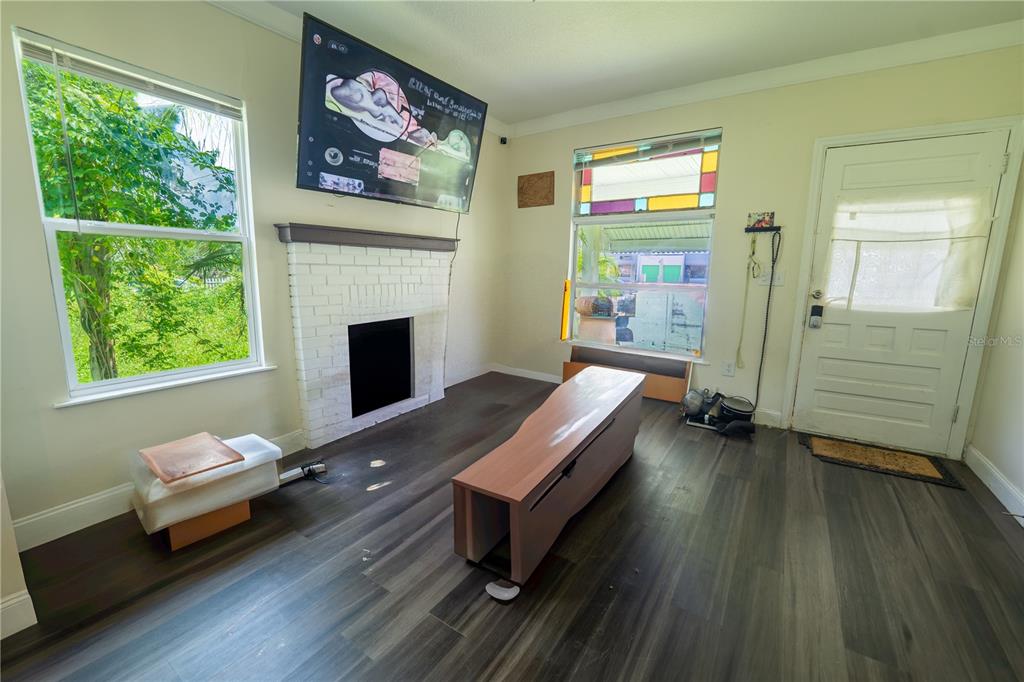 A living room features a white brick fireplace, a wall-mounted television, and wood-look flooring — 2024 OLD LAKE MARY ROAD, SANFORD, FL