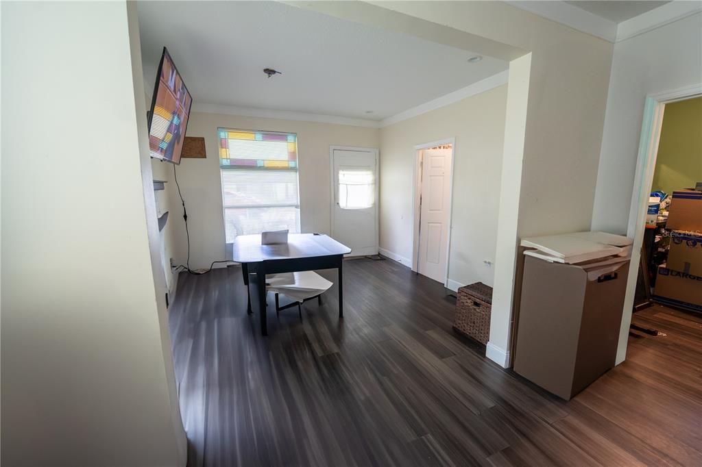 A room with dark wood-look flooring, a central table, a window, and two doorways — 2024 OLD LAKE MARY ROAD, SANFORD, FL