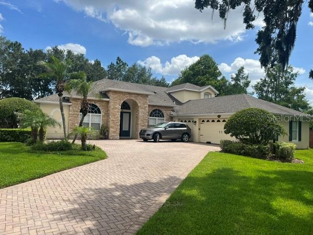 A single-story house with a stone facade, a paved driveway, and a parked silver SUV — 13856 GLYNSHEL DRIVE, WINTER GARDEN, FL