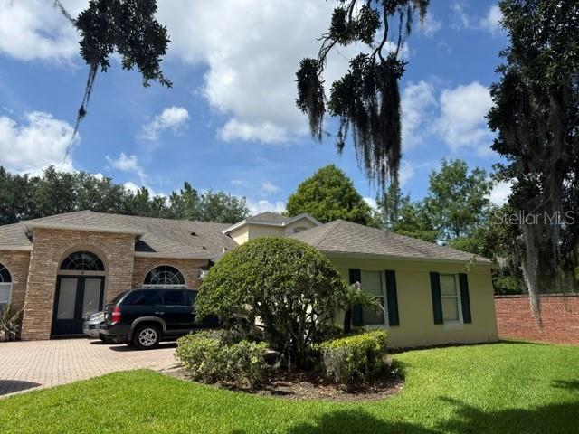 A single-story house with stone veneer and light-colored siding sits behind a large green bush — 13856 GLYNSHEL DRIVE, WINTER GARDEN, FL