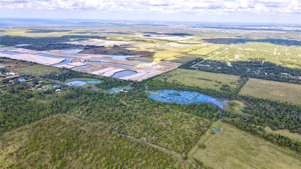 An aerial view shows a large plot of land with cleared construction areas and wetlands — 14266 BURNT STORE ROAD, PUNTA GORDA, FL
