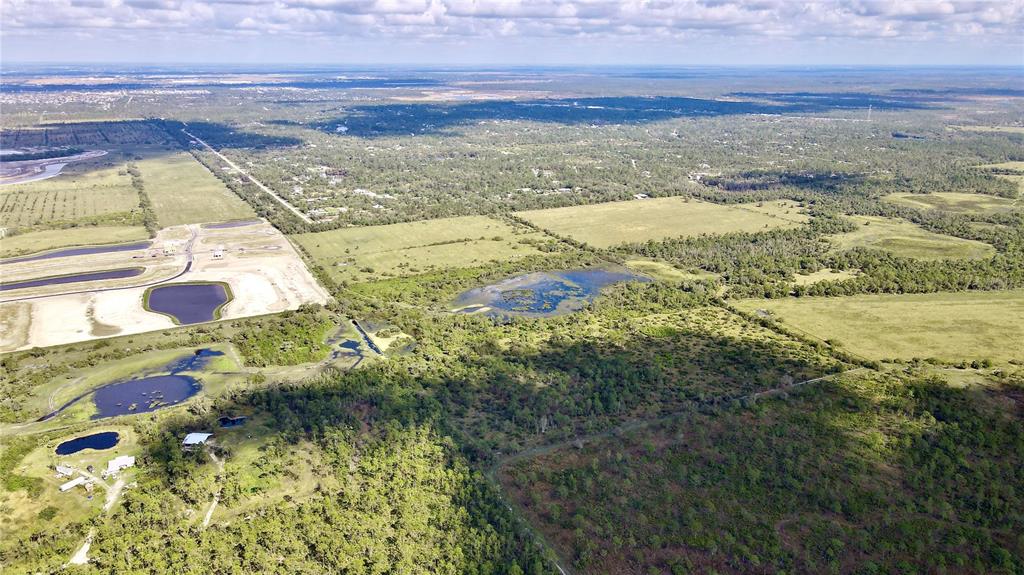 An aerial view shows a large, undeveloped rural landscape with scattered ponds and forested areas — 14266 BURNT STORE ROAD, PUNTA GORDA, FL