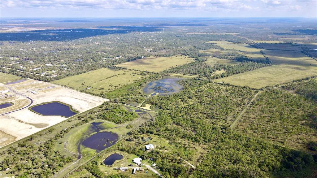 An aerial view shows a rural landscape with ponds, wooded areas, and a small residential property — 14266 BURNT STORE ROAD, PUNTA GORDA, FL