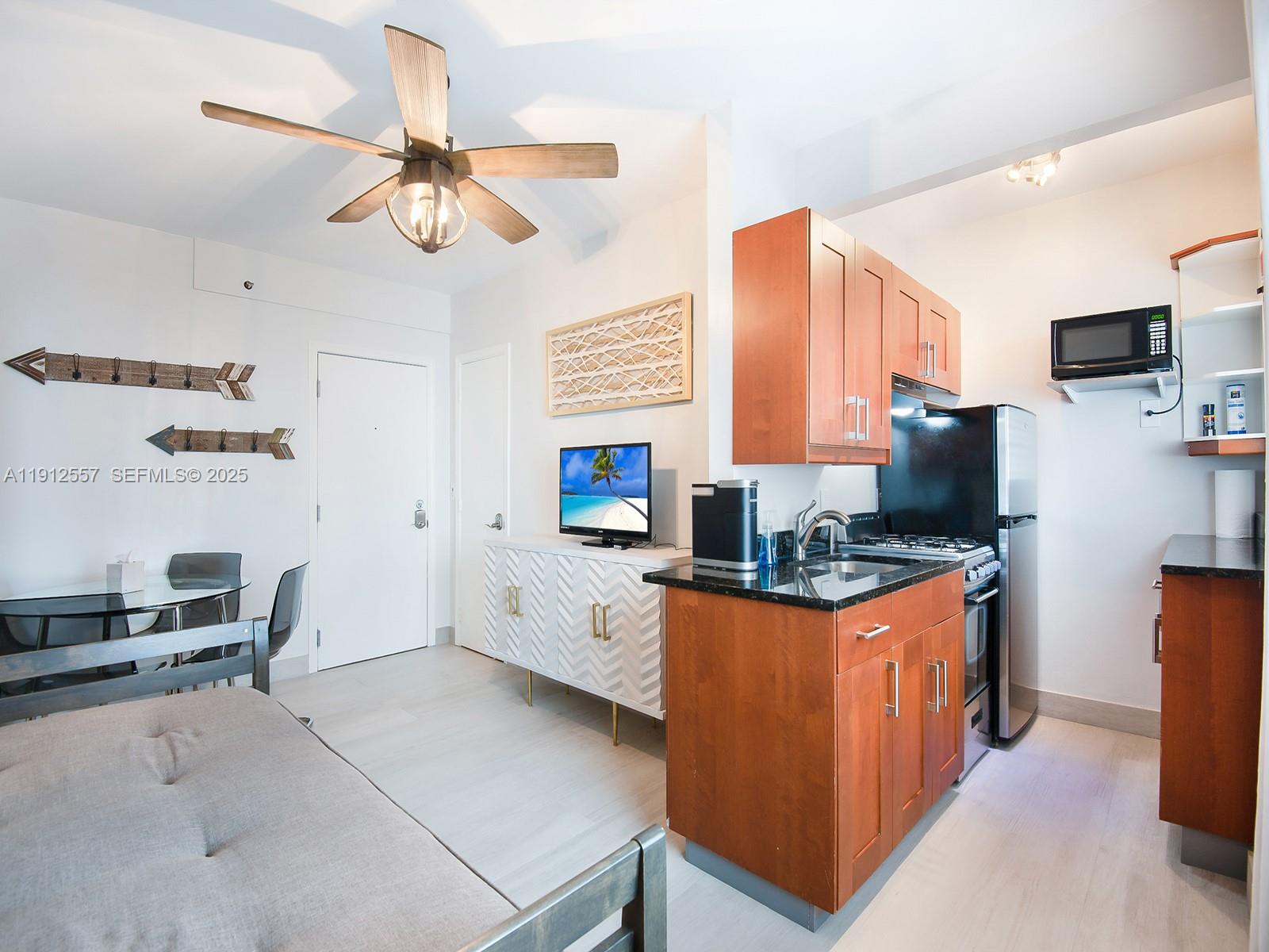 A studio apartment features a kitchen with wood cabinets, a dining area, and a ceiling fan — 335 Ocean Dr # 328, Miami Beach FL 33139, MIAMI BEACH, FL