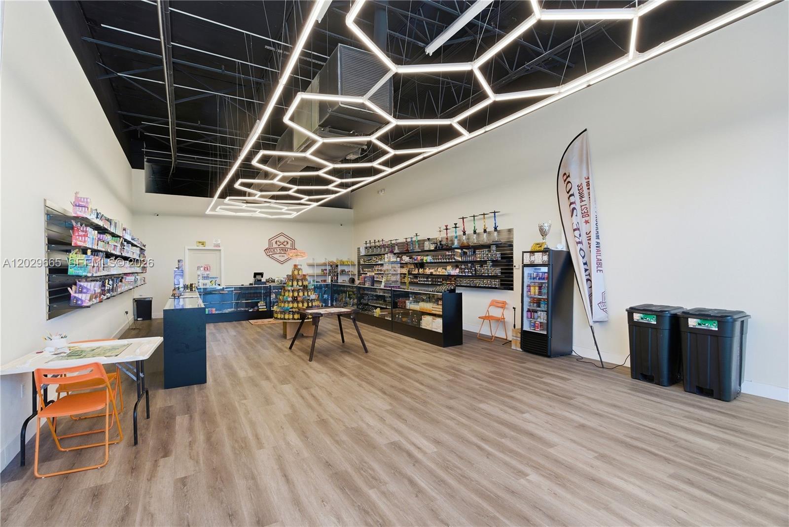 This retail smoke shop features wood-look flooring, a black ceiling, and a geometric LED light fixture — 1815 W okeechobee rd, Hialeah FL 33010, HIALEAH, FL