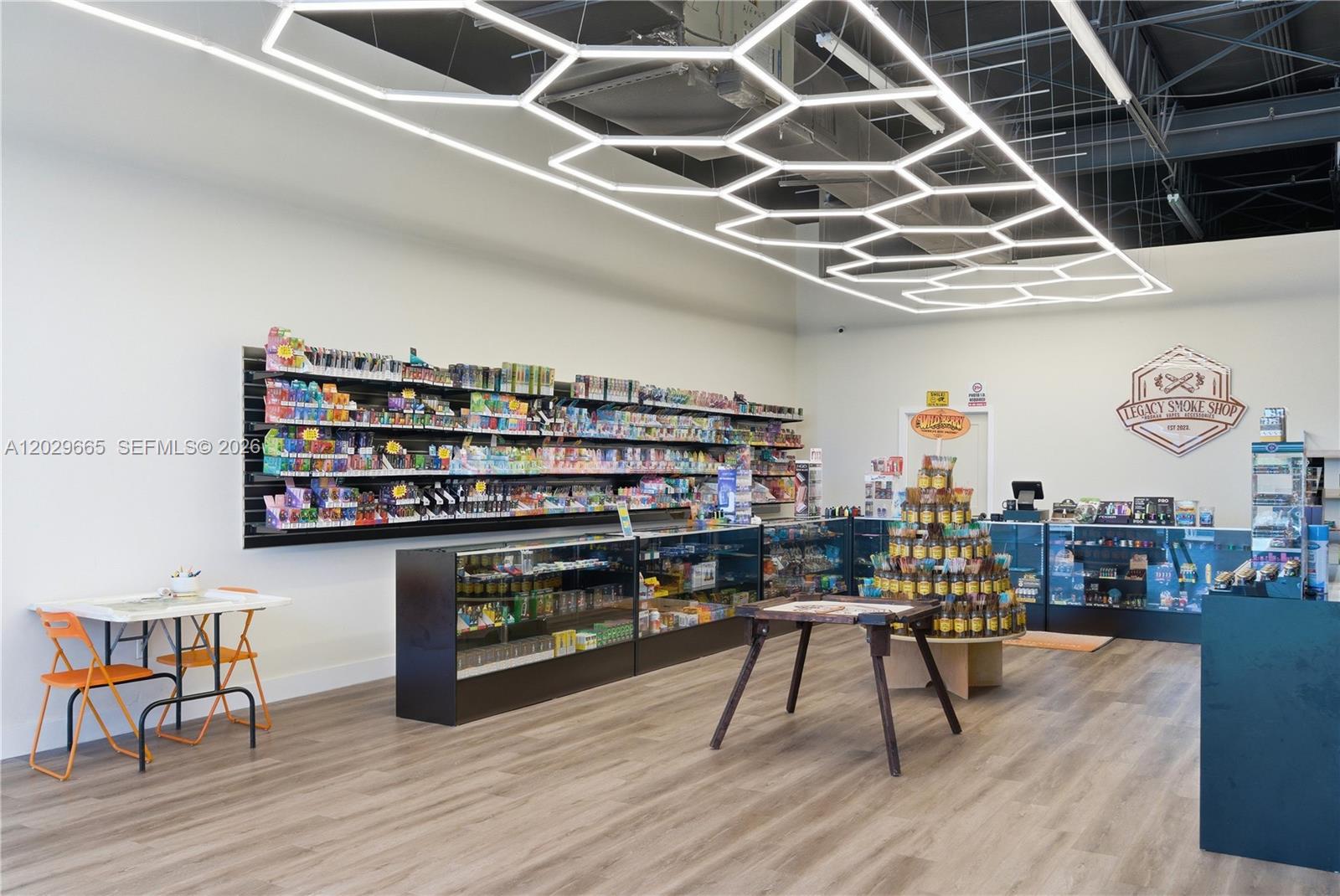 A retail smoke shop interior features wall-mounted shelving, glass display cases, and geometric ceiling lighting — 1815 W okeechobee rd, Hialeah FL 33010, HIALEAH, FL