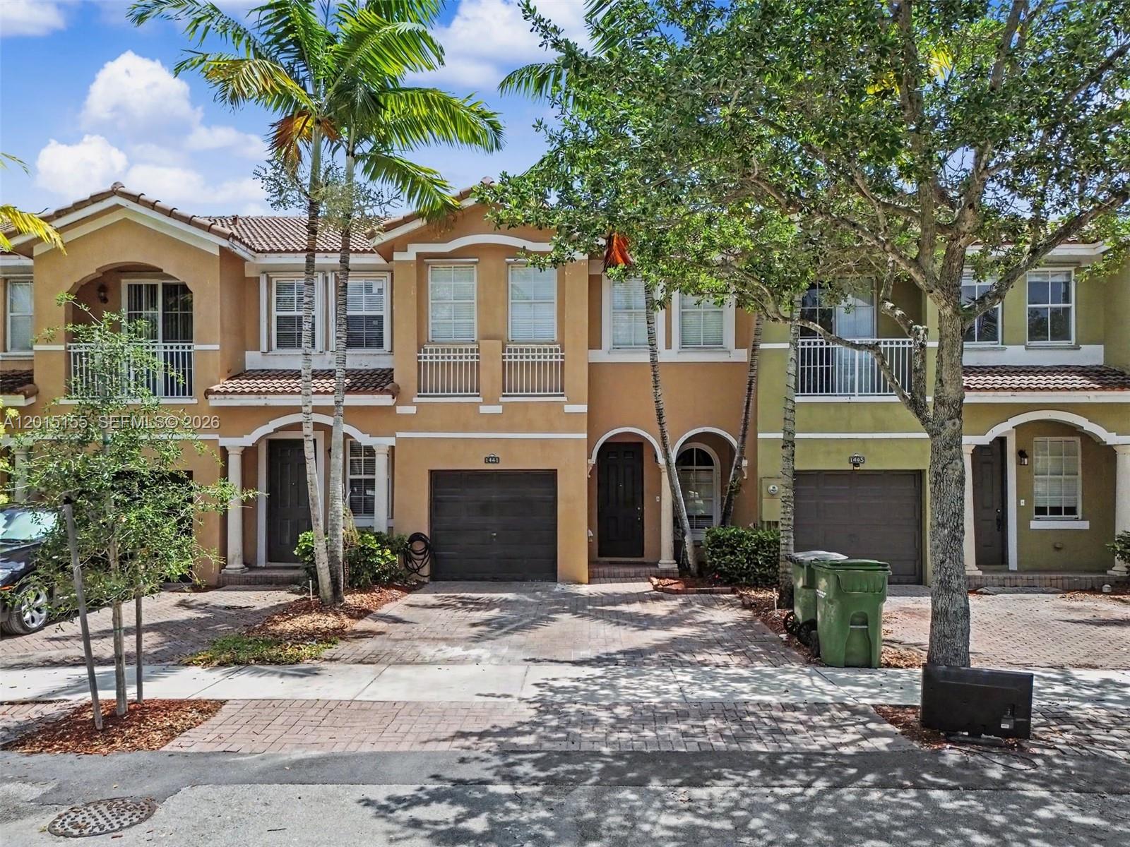 A row of three-story townhouses with garages, balconies, and palm trees in front — 1441 SE 24th Rd, Homestead FL 33035, HOMESTEAD, FL