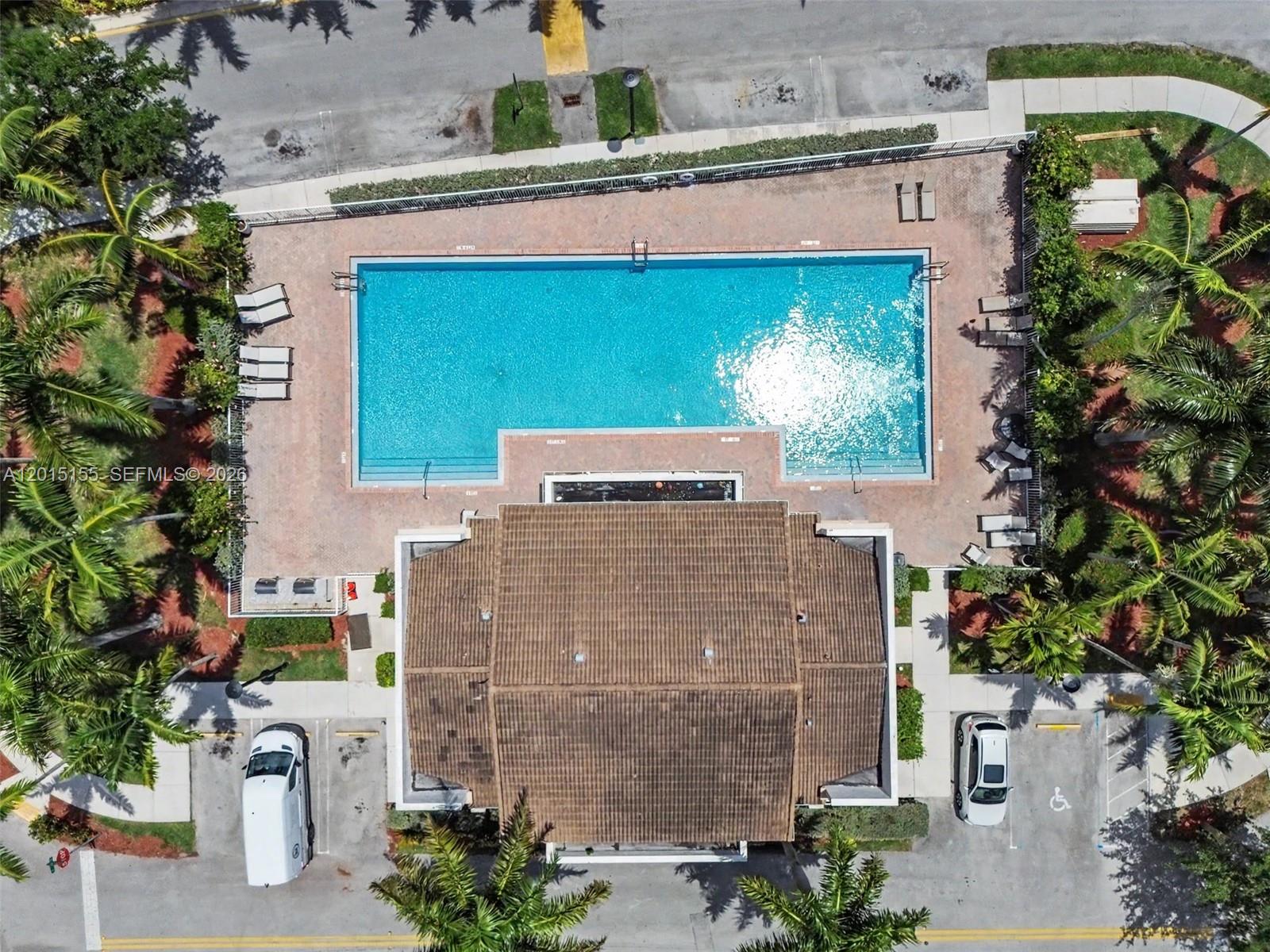 An aerial view shows a rectangular swimming pool with a surrounding patio and a building — 1441 SE 24th Rd, Homestead FL 33035, HOMESTEAD, FL