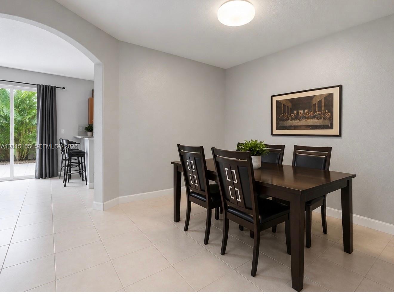 A dining room features a dark wood table and chairs with tile flooring and wall art — 1441 SE 24th Rd, Homestead FL 33035, HOMESTEAD, FL