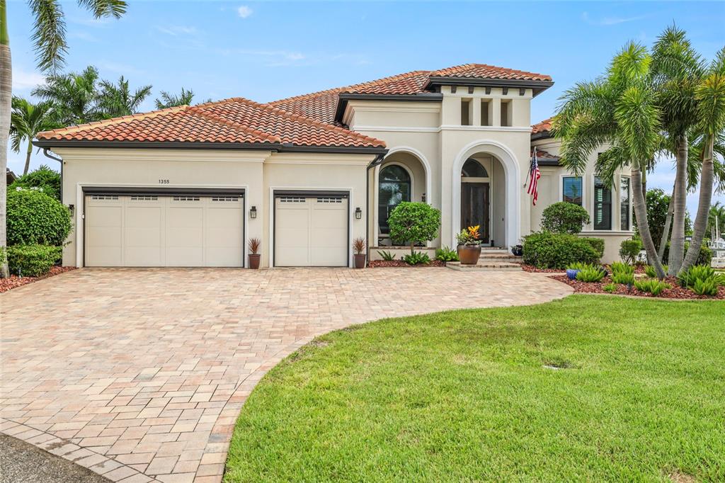 An aerial view of a house with a red tile roof, paver driveway, and waterfront backyard — 1355 GREBE DRIVE, PUNTA GORDA, FL