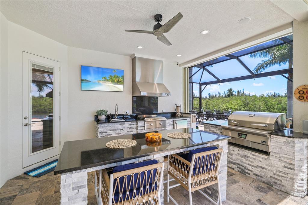 A screened-in patio features a swimming pool, a hot tub, and an outdoor kitchen area — 1355 GREBE DRIVE, PUNTA GORDA, FL