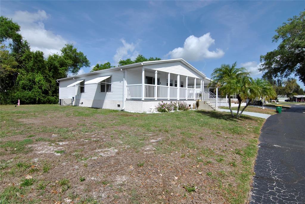 A white manufactured home features a large front porch and a paved driveway — 24437 HARBORVIEW ROAD UNIT 106, PUNTA GORDA, FL
