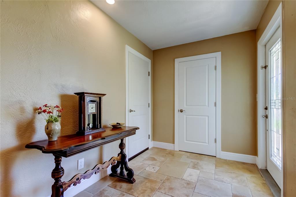 An entryway features a wooden console table, a clock, two white doors, and tile flooring — 4174 14TH LANE NE, ST PETERSBURG, FL