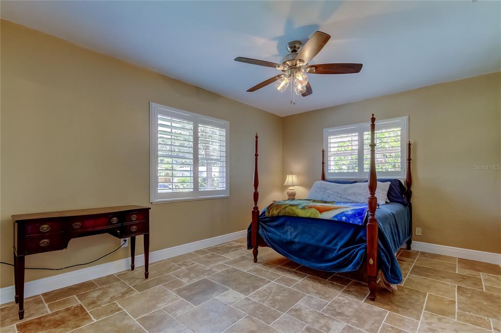 A bedroom features a four-poster bed, a wooden desk, tile flooring, and plantation shutters — 4174 14TH LANE NE, ST PETERSBURG, FL