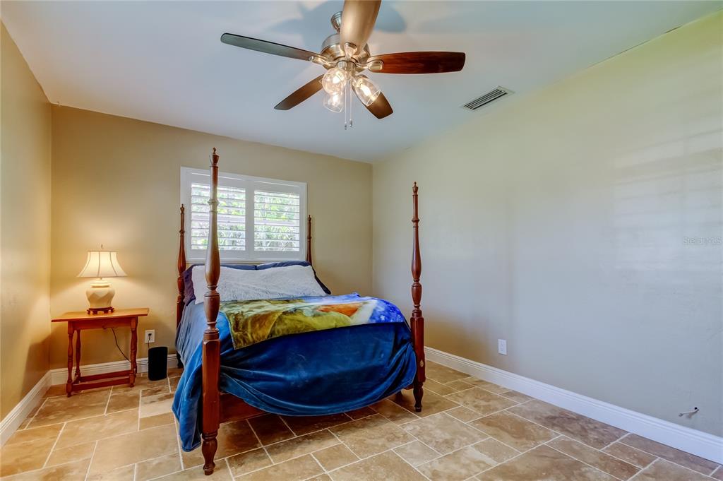 A bedroom features a four-poster bed, tile flooring, a ceiling fan, and a side table — 4174 14TH LANE NE, ST PETERSBURG, FL