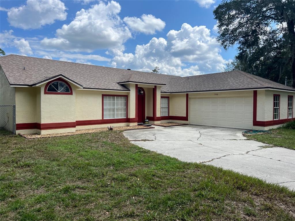 A single-story house with a beige stucco exterior, red trim, and a concrete driveway — 330 BONNIE LANE, ORANGE CITY, FL