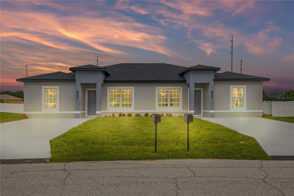 A single-story duplex with gray stucco siding, two front entrances, and two concrete driveways — 476-474 COLUMBIA COURT, POINCIANA, FL