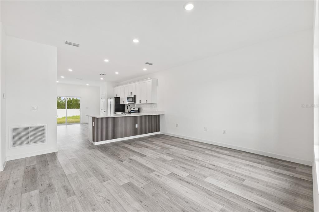 An open-concept kitchen with white cabinets and a gray slatted island overlooks a living area — 476-474 COLUMBIA COURT, POINCIANA, FL