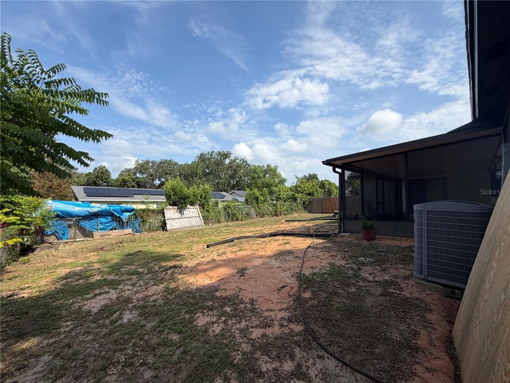 A screened-in patio overlooks a backyard with a fence, trees, and a neighboring house — 2262 MENOMONEE COURT, ORLANDO, FL