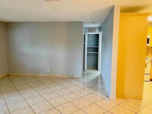 An interior room with light gray walls, beige tile flooring, and a walk-in closet — 4491 NW 1st Terrace, Deerfield Beach FL 33064, DEERFIELD BEACH, FL